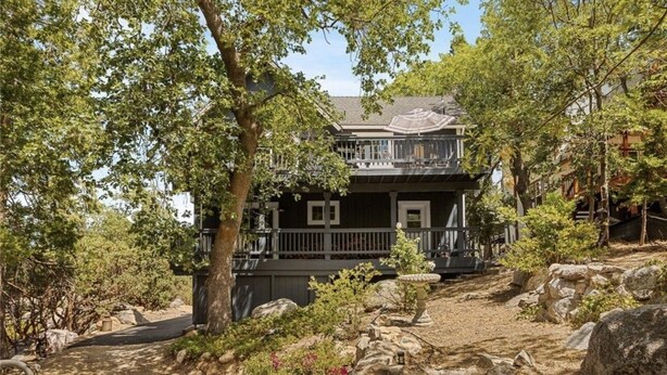 Un bâtiment à deux étages doté d’un balcon, entouré d’arbres et de rochers.