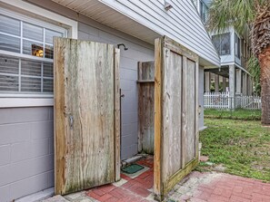 A house with a wooden door partially open, revealing a small interior space. - Great Family Beach House | Heated Pool Access (Tybee Island)