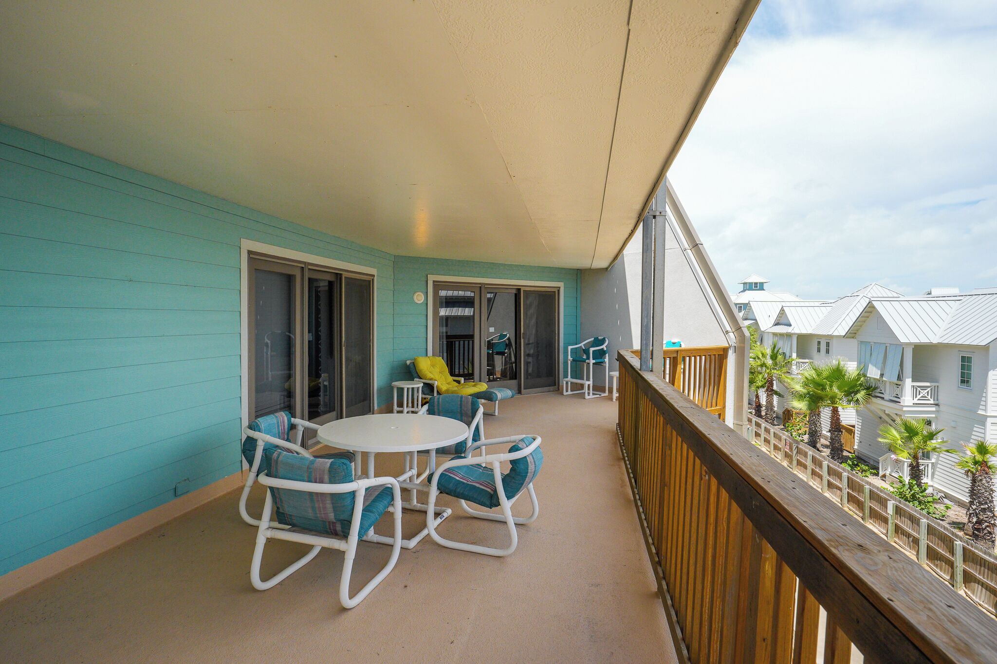 A balcony with a table and chairs, a sliding glass door, and a view of other buildings.