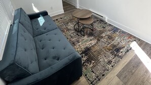 A modern living room with a sectional sofa, a small round table, and a patterned rug. - Crystal Sands Apartments  (Ocean City)