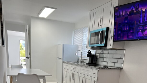 A modern kitchen with white cabinets, a granite countertop, and a built-in microwave. - Crystal Sands Apartments  (Ocean City)