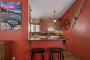 Una cocina con armarios de madera, una isla de acero inoxidable y un reloj en la pared.