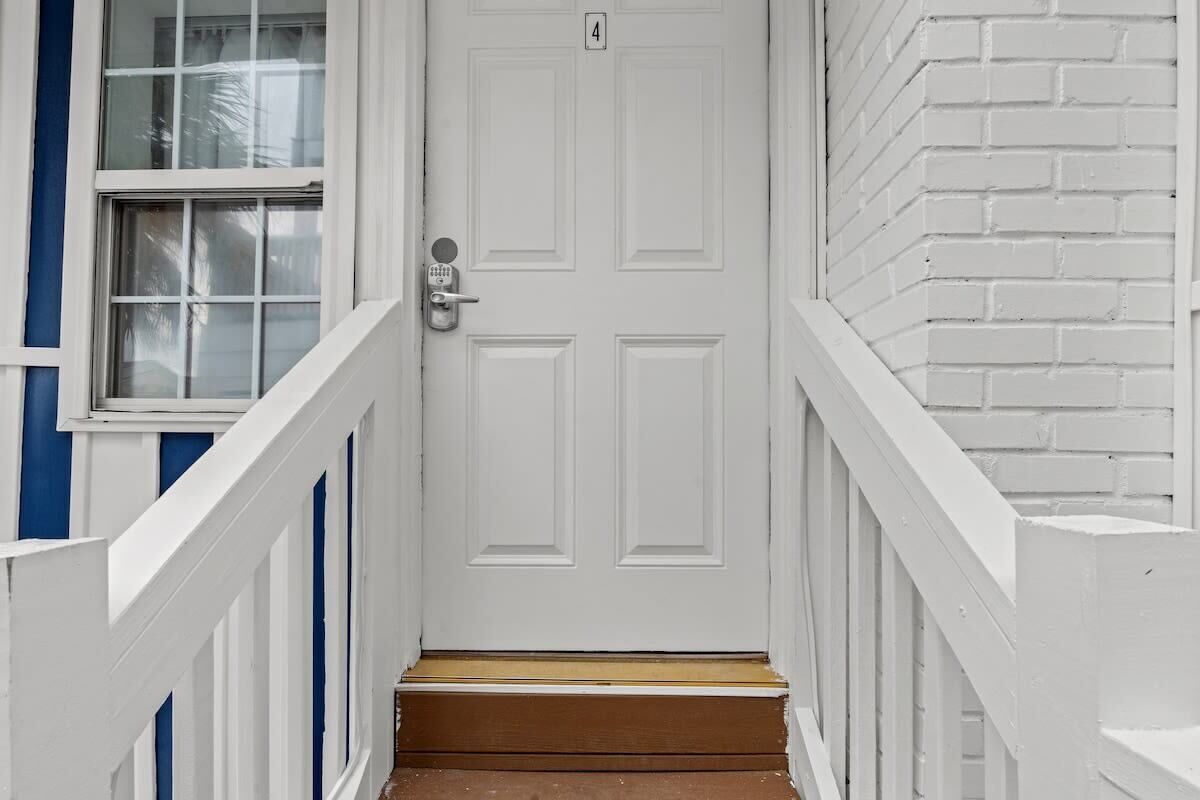 A white door with a number 4 sign above it, leading to a wooden staircase.