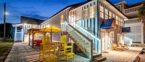 A modern building with a staircase, outdoor seating area with yellow chairs, and a covered patio.
