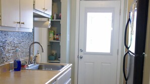 Une cuisine avec un plan de travail en bois, un évier, une poubelle et un réfrigérateur.