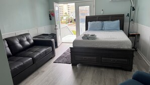 Une chambre à coucher avec un lit, un canapé en cuir noir, une petite table et une table de chevet.