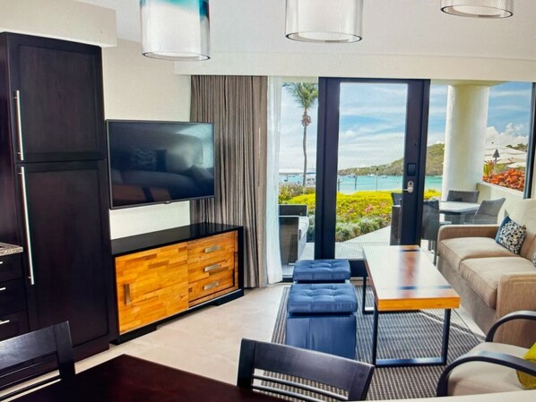 A modern living room with a flat-screen TV, wooden cabinet, and a sofa.
