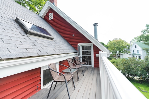 A red house with a covered porch, a skylight, and a chimney.