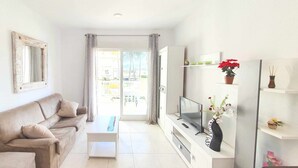 A living room with a sofa, TV, and a small table. - Apartment in urbanization near the beach (Denia)