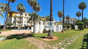 A hotel courtyard with palm trees, a swimming pool, and a clear blue sky. - Apartment in urbanization near the beach (Denia)