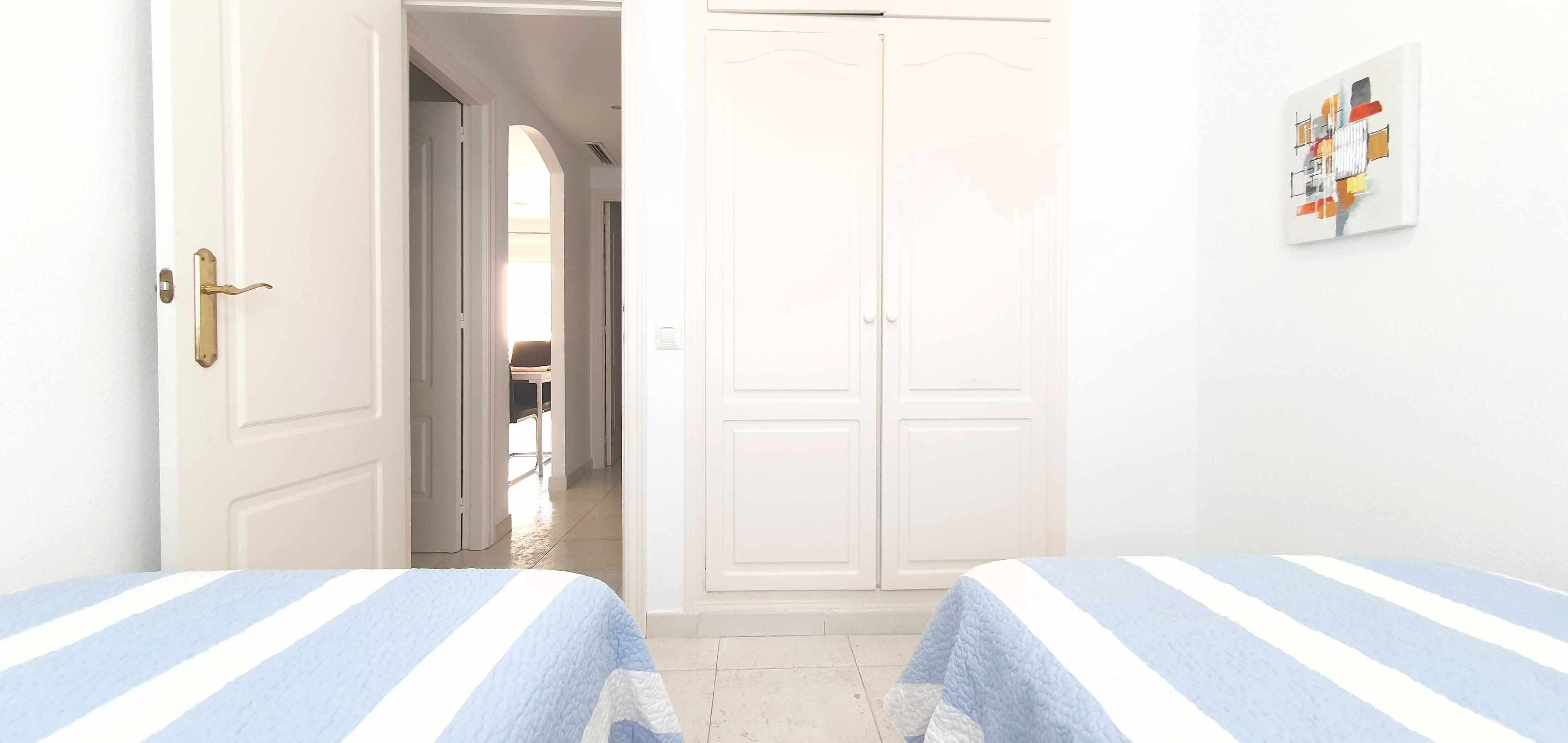 Una habitación con dos camas, un armario y una puerta que da a otra habitación.