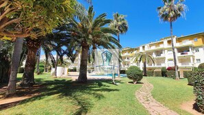 A courtyard with palm trees, a pool, and a building with balconies. - Apartment in urbanization near the beach (Denia)
