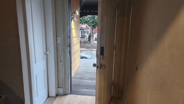 A hallway with a wooden floor, a door leading outside, and a visible street view. - Cozy and stylish apartment in central meriden (Meriden)