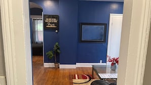 A hallway with blue walls, a wooden floor, a red rug, a framed picture, and a potted plant. - Cozy and stylish apartment in central meriden (Meriden)