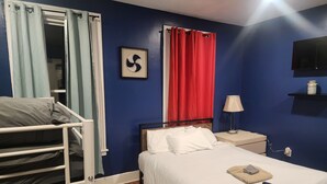 A bedroom with a bunk bed, a single bed, a framed picture, a red curtain, a bedside lamp, and a TV on the wall. - Cozy and stylish apartment in central meriden (Meriden)