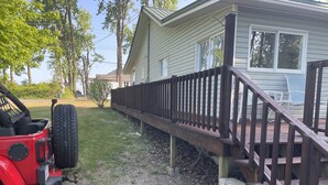 Una casa con un portico in legno e un veicolo rosso parcheggiato davanti.