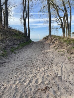 A sandy path leading to a beach with trees on either side. - Newly updated cottage with new central air just steps from the beach (Port Rowan)