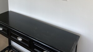 Un muro con un cartello di benvenuto, un'opera d'arte a tema spiaggia e un mobile nero.