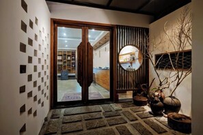 A reception area with a sliding glass door, a reception desk, and a wall with square patterns. - Mini Inn (Zhangjiajie)