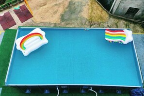 A blue inflatable pool with a rainbow float and a striped float. - Mini Inn (Zhangjiajie)