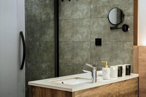 A modern bathroom with a marble sink, a round mirror, and a wooden vanity.
