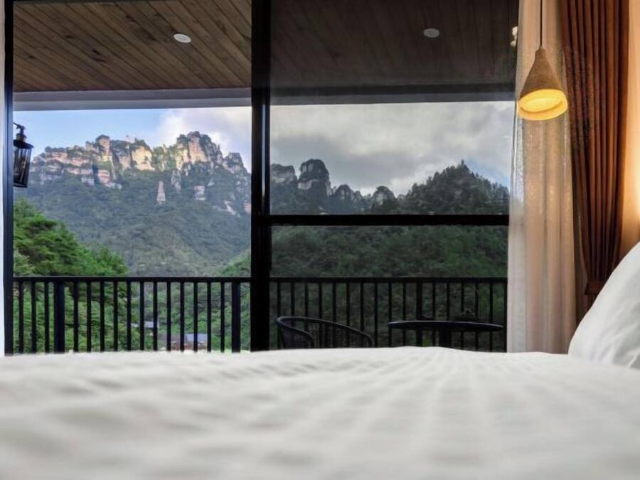 Quarto com uma janela grande, cama, poltrona e mesa.