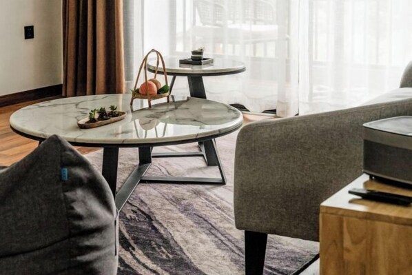 A modern living room with a round marble coffee table, a grey sofa, and a television on a wooden stand.