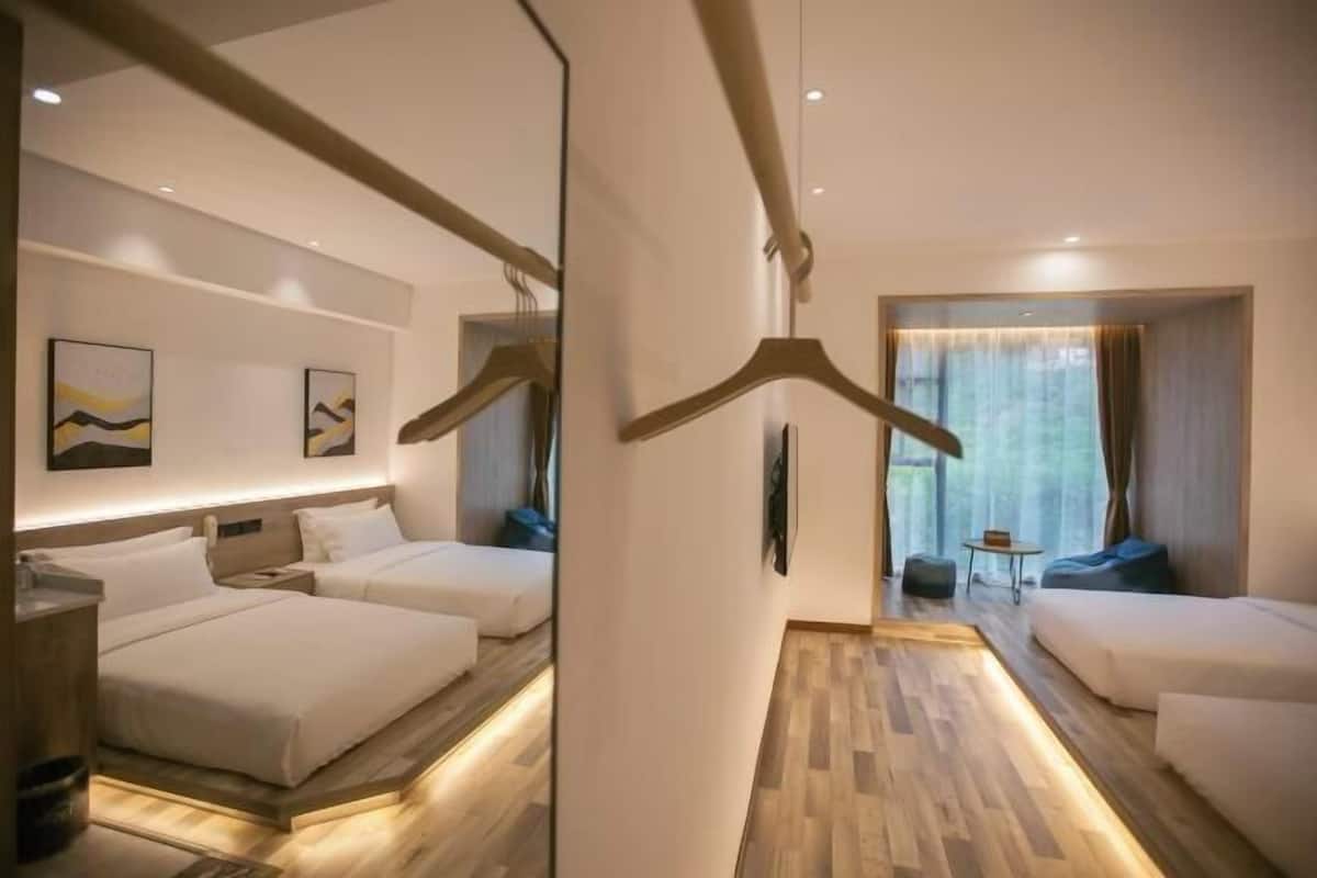 A hotel room with two beds, a sofa, a small table, and a mirror.