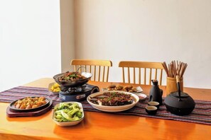 Una mesa con varios platos, palillos y una tetera.