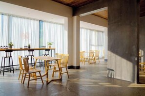 A spacious room with a long table and chairs, large windows with sheer curtains, and a concrete pillar. - Mini Inn (Zhangjiajie)