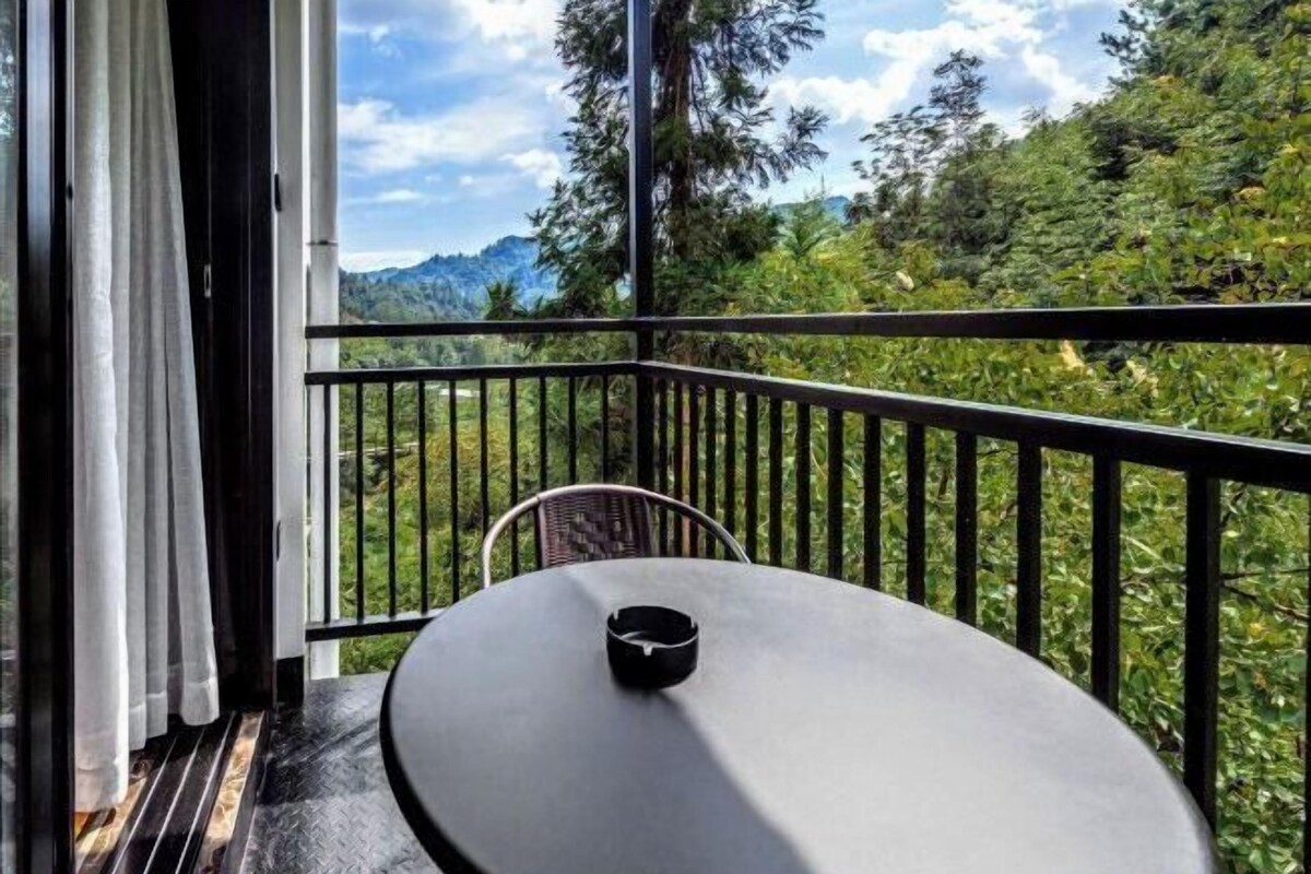 A balcony with a table and chair, overlooking a mountainous landscape.