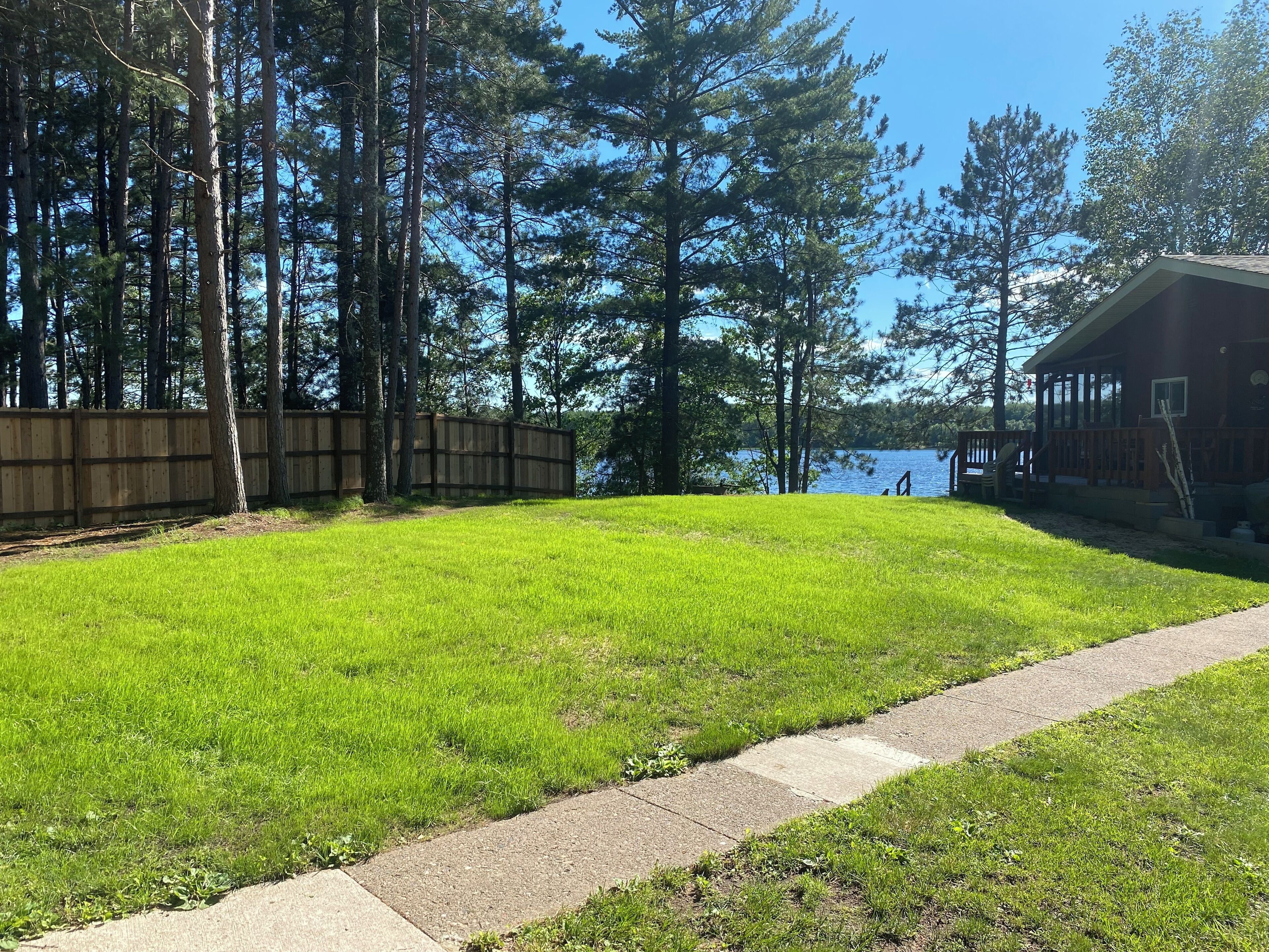 A grassy area with a wooden deck and a building with a view of a lake.