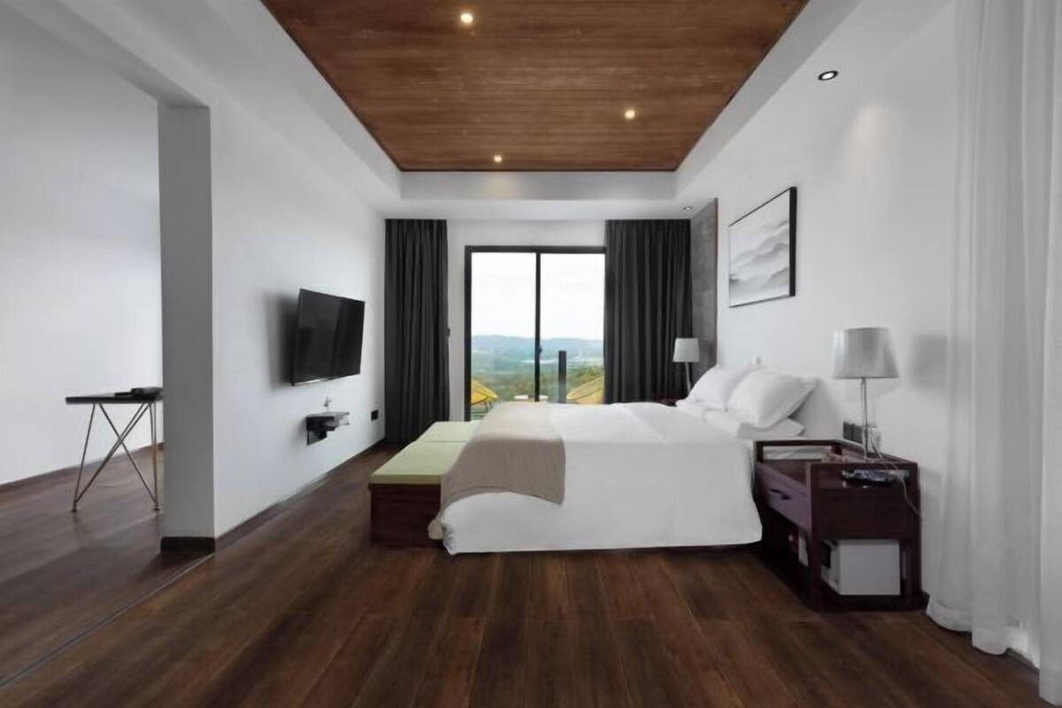 Habitación de hotel moderna con una cama grande, un televisor de pantalla plana, un escritorio y vistas al exterior.
