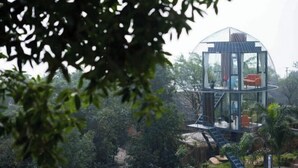 Estructura de cúpula de cristal transparente con una escalera que lleva a una plataforma con asientos.