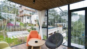 Una habitación moderna con ventanas amplias, techo de madera y vista a una zona residencial.