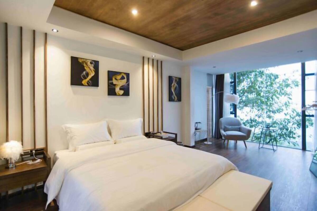 Un dormitorio moderno con una cama grande, una mesita de noche, una silla y una obra de arte en la pared.