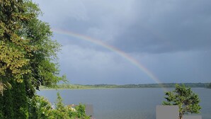 A deck with a view of a lake and a rainbow. - Beautiful lakefront property on Barton Lake with Hot Tub! (Vicksburg)