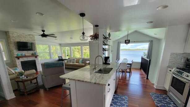 A spacious kitchen with a large island, a dining area with a view, and a cozy living room with a fireplace. - Beautiful lakefront property on Barton Lake with Hot Tub! (Vicksburg)