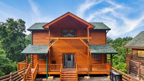Eine Blockhütte mit einer Veranda, einer Treppe zum Eingang und einem kleinen Wintergarten an der Seite.