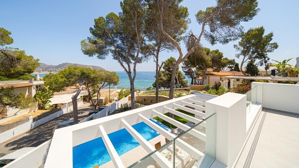 Et tagområde med pool, hvor man kan se klart ud over havet og de omkringliggende bygninger.