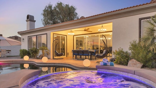Uma casa moderna com piscina, móveis de pátio e hidromassagem.