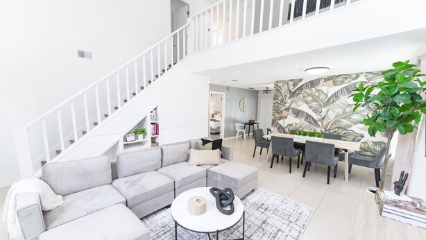A modern living room with a grey sectional sofa, a round coffee table, and a staircase leading to an upper level.