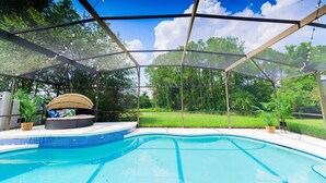 A covered swimming pool with a seating area and a view of a grassy landscape.