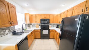 A modern kitchen with wooden cabinets, a black refrigerator, a microwave, and a dishwasher.