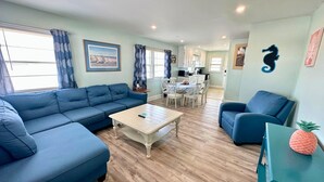 Ein Wohnzimmer mit einem blauen Sofa, einem Couchtisch und einem Türkistisch mit einer Ananas-Dekoration.