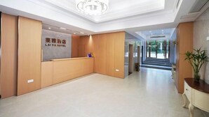 A hotel reception area with a modern design, featuring a reception desk, a chandelier, and a view of the outdoor area through the glass doors. - Laiya Boutique Hotel (Southwest University Zhuangyuanbei Subway Station) (Chongqing)