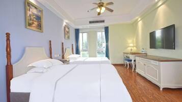 A hotel room with a large bed, a desk, a television, and a ceiling fan.