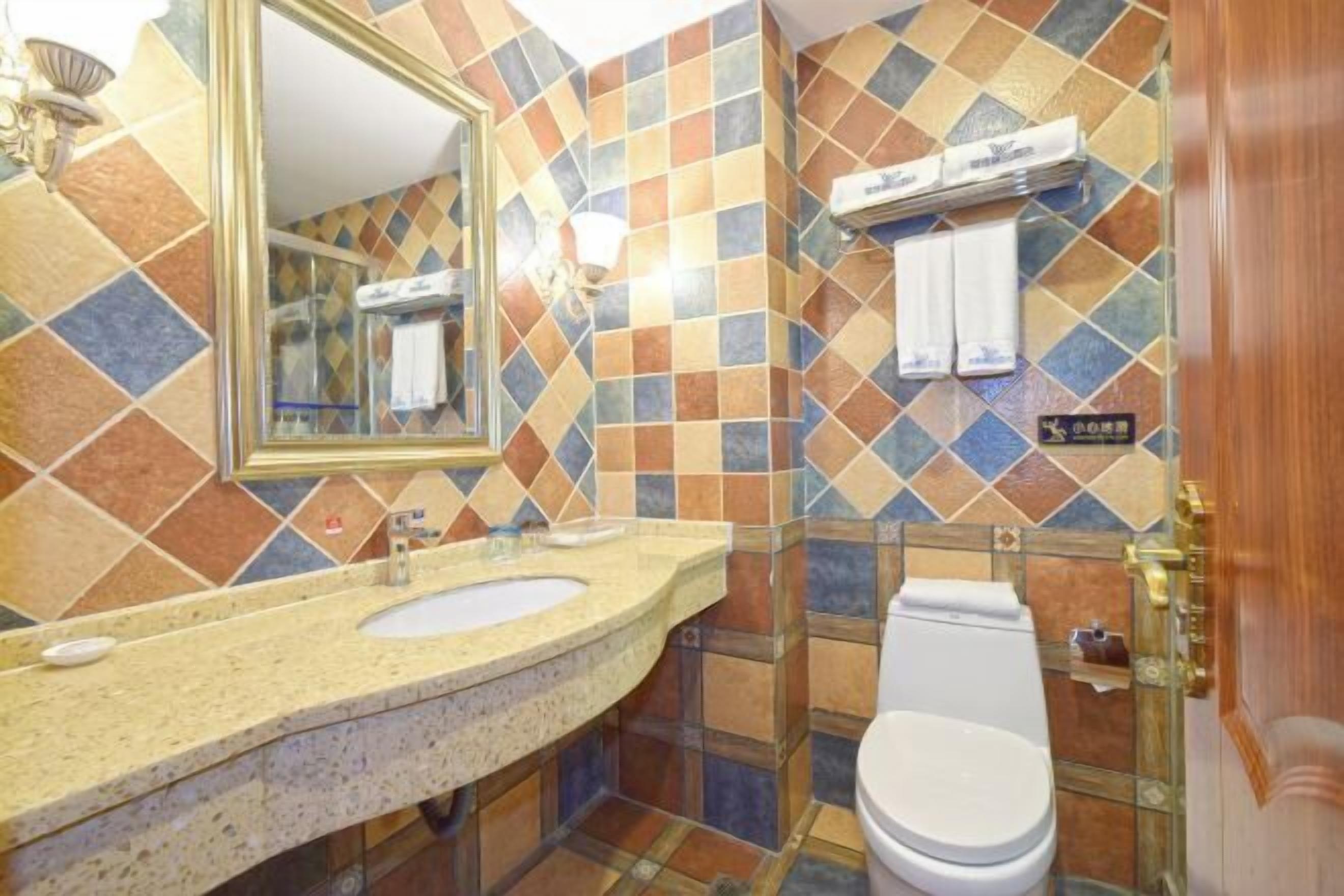 A bathroom with a tiled wall, a sink, a toilet, and a mirror.