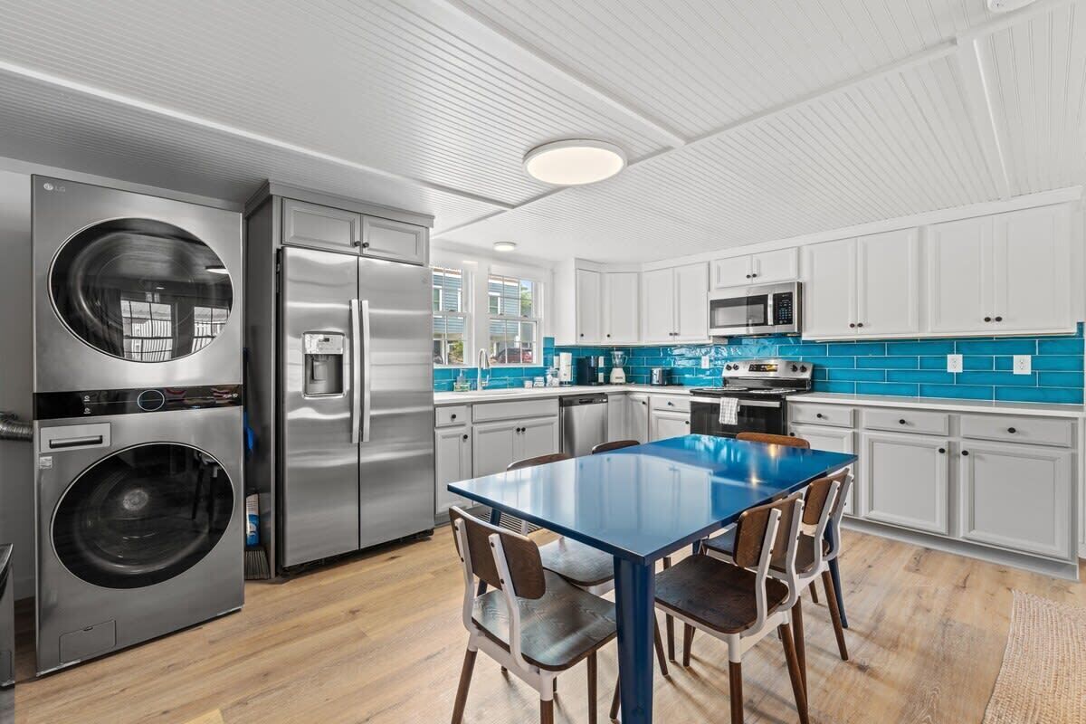 A modern kitchen with stainless steel appliances, a blue-tiled backsplash, and white cabinetry.