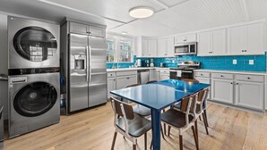 A modern kitchen with stainless steel appliances, a blue-tiled backsplash, and white cabinetry.